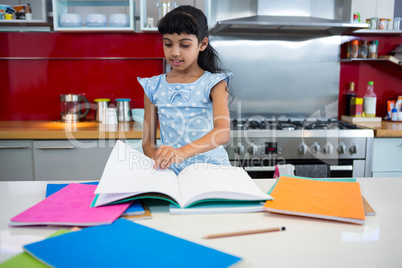 Girl flipping pages of book in kitchen