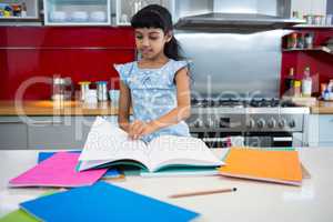 Girl flipping pages of book in kitchen