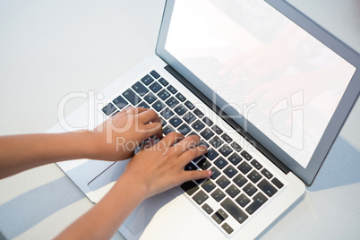 High angle view of girl typing on laptop keyboard