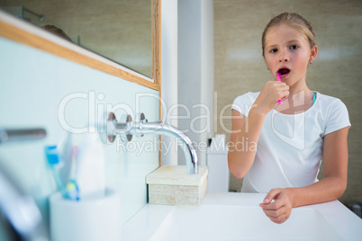 Portrait of girl brushing teeth in bathroom