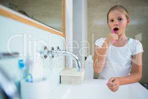 Portrait of girl brushing teeth in bathroom