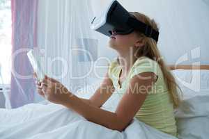Girl holding tablet while wearing virtual reality simulator