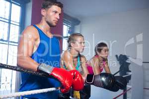 Young male boxer standing by female athletes