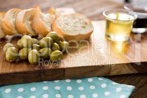 Olive oil with olive and bread kept on chopping board