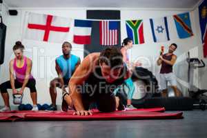 Young male athlete praticing push ups on exercise mat