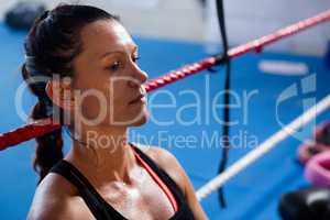 Thoughtful female boxer leaning on rope