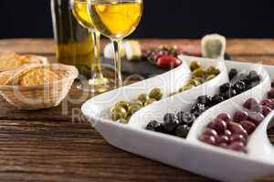 Close-up of marinated olives with bottle of wine and food