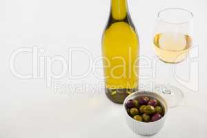 Close-up marinated olives with glass and bottle of wine