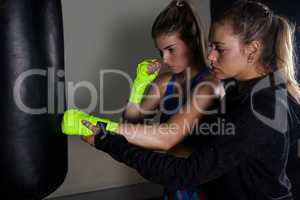 Trainer assisting woman in boxing