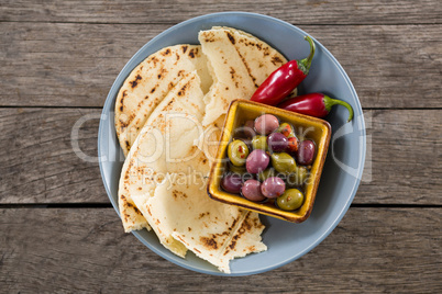 Marinated olives, food and chili pepper on wooden table