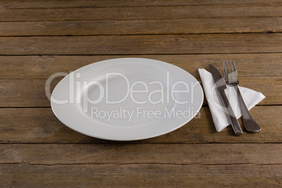 White plate with cutlery and napkin on table