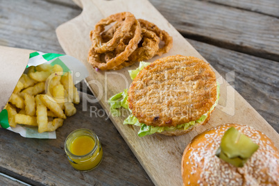 High angle view of burger with onion rings and french fries on cutting board