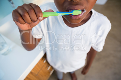 Midsection of boy brushing teeth by sink