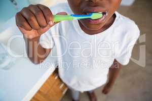 Midsection of boy brushing teeth by sink