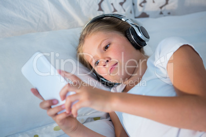 High angle view of girl listening music while using smartphone