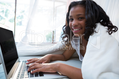Portrait of girl using laptop on bed