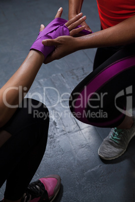 Trainer tying hand wrap on woman hand