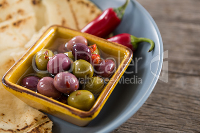 Marinated olives, food and chili pepper on wooden table