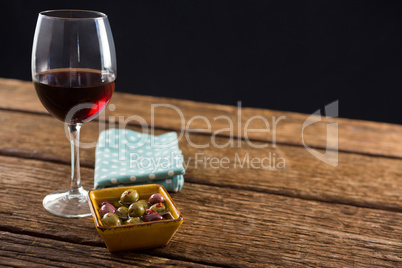 Close-up of marinated olives with glass of wine