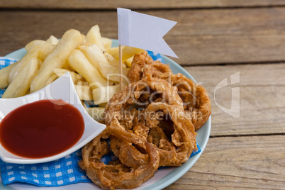 Onion ring and french fries with ketchup arranged in plate