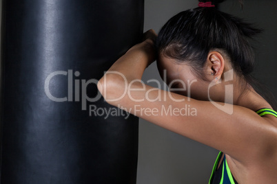 Exhausted female boxer leaning on punching bag