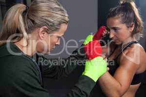 Trainer assisting woman in boxing