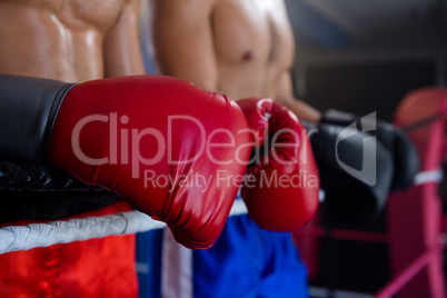 Midsection of male boxers standing by rope