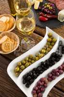 Close-up of marinated olives with bottle of wine and food