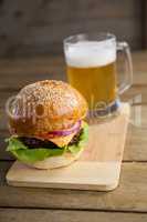 Burger with glass of beer on chopping board