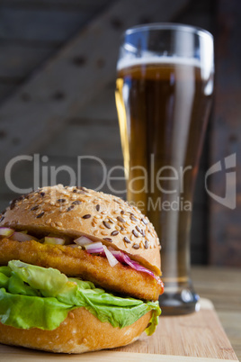 Burger with glass of beer on chopping board