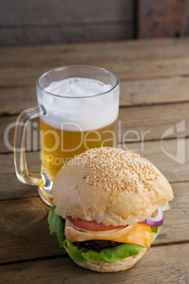 Burger with glass of beer on wooden table