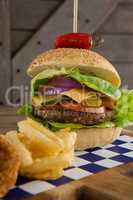Hamburger and french fries on chopping board