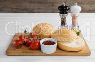 Buns, cherry tomato, sauce on chopping board