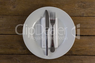 White plate with cutlery and napkin on table