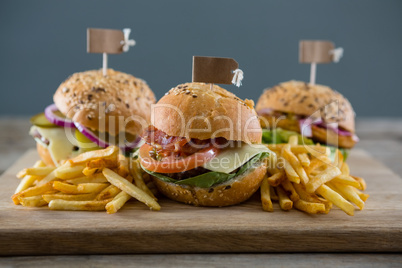 Close up of burgers with french fries served on cutting board