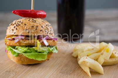 Burger with French fries on cutting board