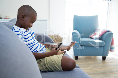 Side view of boy using mobile phone while sitting on sofa