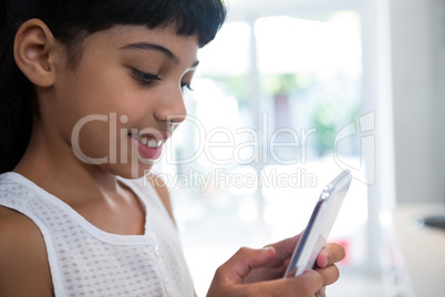 Close-up of girl texting from mobile phone in kitchen
