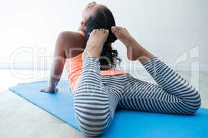 Full length of girl doing raja bhujangasana in room