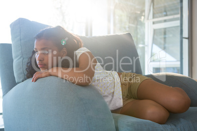 Thoughtful girl leaning on armchair