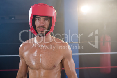 Portrait of shirtless male boxer wearing red headgear