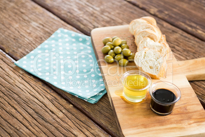 Olive oil with olive and bread kept on chopping board