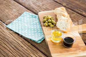 Olive oil with olive and bread kept on chopping board