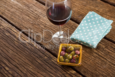 Close-up of marinated olives with glass of wine