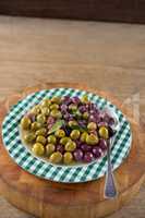 Marinated olives with herbs on wooden board