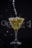 Martini splashing into glass with olives