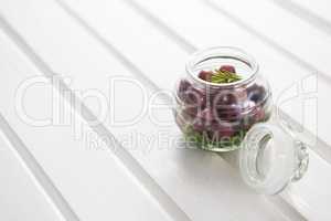 Marinated olives with herbs in a glass jar on table