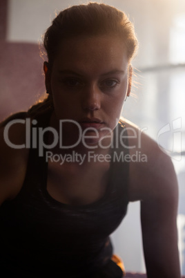 Confident woman sitting in boxing ring