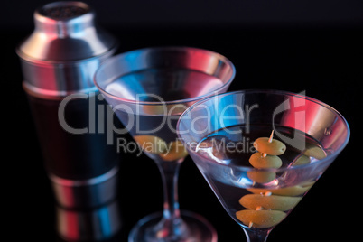Cocktail martini with olives and shaker on table