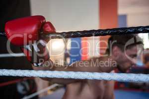 Side view of tired male boxer holding rope